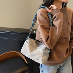 Close-up of light gray nylon tote bag with a wide colorful jacquard woven shoulder strap