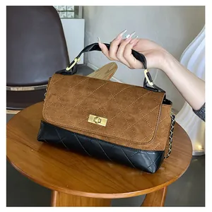 Detail of bicolor quilted handbag featuring brown suede flap and golden twist lock