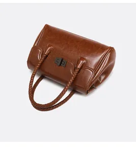 Détail du sac Boston en cuir marron avec poignées tressées et fermoir pivotant chromé