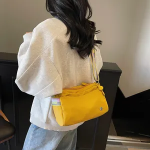 Detail view of bright yellow nylon tote bag with contrasting purple woven shoulder strap