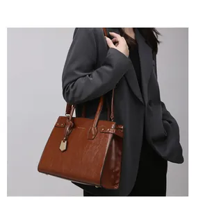 Detail of a brown vintage leather handbag with metallic rivets and a gold pendant charm