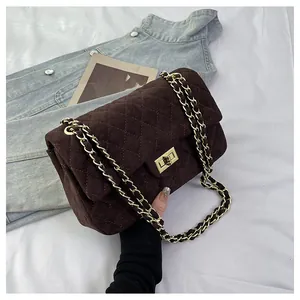 Close-up of brown quilted velvet bag with gold twist lock and metal chain strap