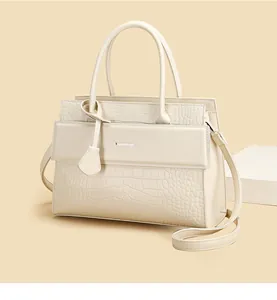 Detail of cream crocodile pattern tote bag with metal logo and adjustable strap