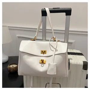 Close-up of white leather tote bag featuring golden twist locks on a suitcase