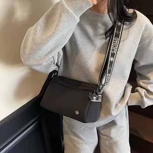 Close-up of black nylon crossbody bag with wide jacquard strap and metal logo detail