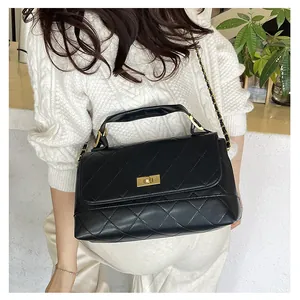 Close-up of quilted pattern and gold metal twist lock on black leather shoulder bag