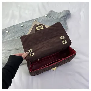 Detail view of the velvet quilted bag showing the red interior lining and chain strap