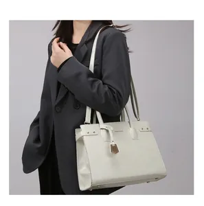 Detailed macro view of the structured cream tote bag featuring golden hardware and logo