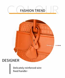 Detail of orange crocodile embossed handbag showing reinforced handle with fine stitching