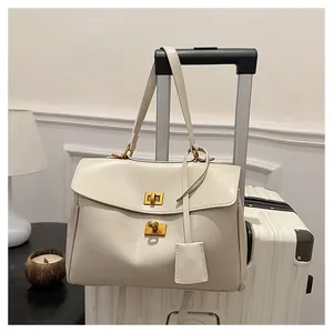 Detail of cream leather shoulder bag with gold twist locks hanging on suitcase handle