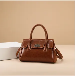 Détail d'un sac cabas marron vintage avec poignées tressées et boucle rotative en métal