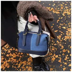 Chic boston bag with blue denim and leather patchwork shown in an autumn street scene