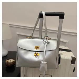 Detail of silver metallic leather tote bag with gold twist locks on white suitcase
