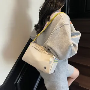Detail of off-white canvas tote with colorful jacquard strap and brand logo pendant