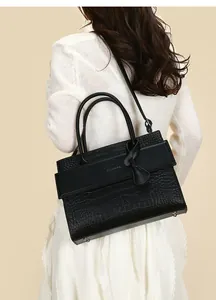 Close-up of black crocodile embossed tote bag with silver studs and smooth flap detail