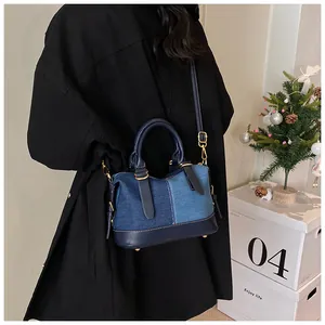 Detail showing contrast denim patchwork handbag with premium blue leather and gold hardware