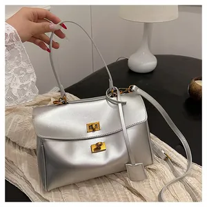 Detail of silver metallic tote bag with dual gold twist locks and leather strap