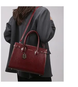 Detail of wine red oil wax leather handbag with gold hardware and studded straps