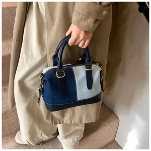Close-up of contrast denim boston bag with golden zippers and leather handles