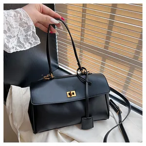 Detail of black leather handbag featuring a gold rectangular twist lock and fine texture