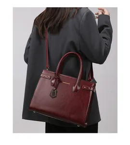 Detail view of burgundy leather handbag showing the polished finish and golden logo