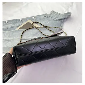 Macro detail of black quilted bucket bag featuring gold chain and brown inner lining