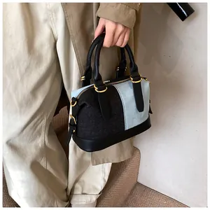 Close-up of contrast denim handbag with black leather handles and gold metal hardware