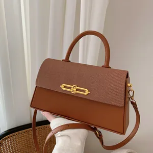 Detail der braunen Handtasche mit Stofftextur und goldenem Metallschloss-Verschluss