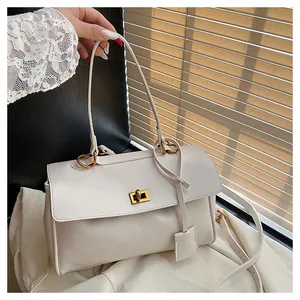 Detail of off-white shoulder bag featuring a gold twist lock and fine leather texture