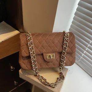 Brown quilted velvet crossbody bag with gold chain strap and vintage buckle on books