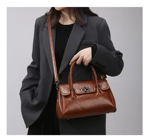 Détail du sac à main marron avec poignées tressées et fermoir rotatif en métal argenté
