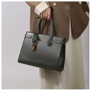Close-up of structured dark grey handbag with gold metal accents and fashion lettering