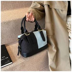 Detail of color-block Boston bag featuring tweed and corduroy patchwork with gold hardware