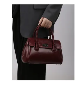 Gros plan du sac cabas bordeaux en cuir ciré avec poignée tressée et fermoir en métal