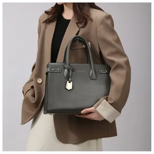 Detail of dark green textured leather tote bag carried by model in stylish suit