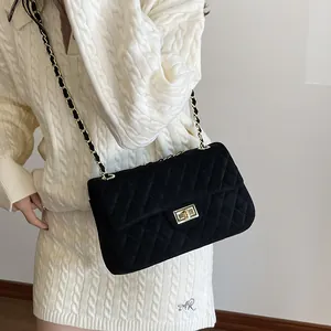 Classic black velvet quilted chain crossbody bag with golden clasp worn by a model