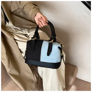 Detailed close-up of two-tone denim patchwork handbag with gold metal hardware