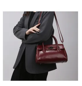 Détail du cabas bordeaux en cuir ciré avec poignées tressées et fermoir rotatif noir