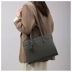 Detail of dark green leather tote bag with gold hardware and side rivet accents