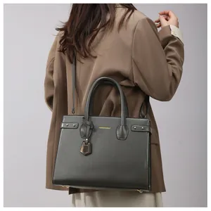 Dark grey leather handbag with adjustable strap shown on model in brown blazer jacket