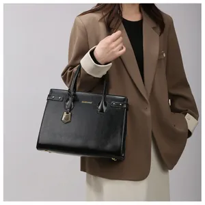 Detail of black leather handbag with gold logo lettering shown on a female model
