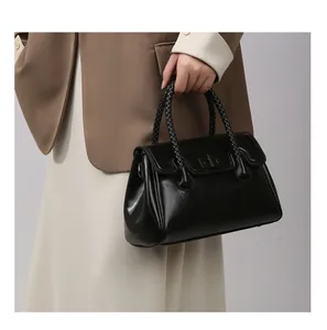 Détail d'un sac à main noir en cuir avec poignée tressée et fermoir métallique chic
