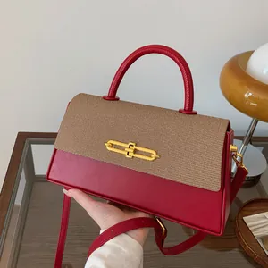 Detail der rot-braunen Handtasche mit edlem goldenem Kettenschloss und Leder-Schultergurt