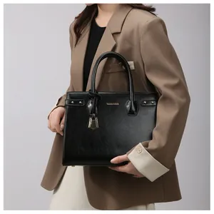 Detail of black leather handbag with gold rivets and decorative geometric pendant