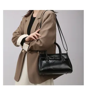 Détail du sac cabas en cuir noir avec poignée tressée et fermoir rotatif en métal