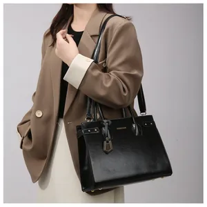 Woman carrying a shiny black faux leather handbag with shoulder strap for commuting
