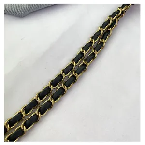 Close-up of vintage gold metal chain interlaced with black leather strap for handbag
