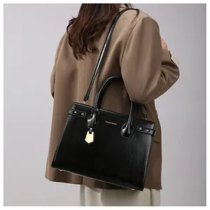 Detail of black matte handbag with gold hardware and logo shown on a fashion model