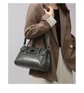 Détail d'un sac cabas vert foncé avec poignées tressées et bandoulière élégante