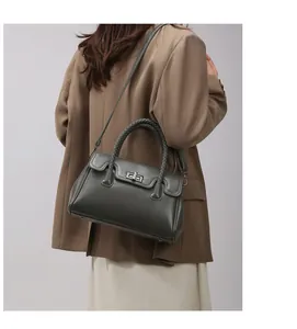 Détail d'un sac cabas gris-vert foncé avec poignée tressée et fermoir rotatif en métal